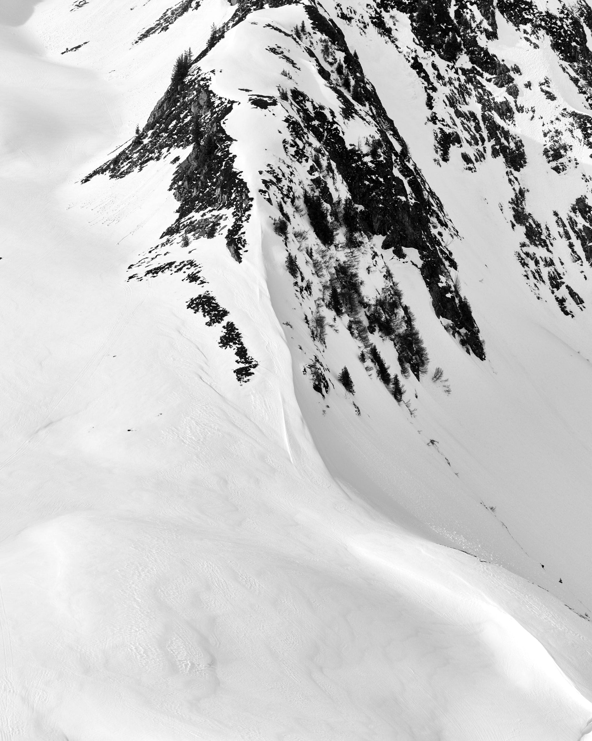 The artpiece 'Abhang' by Andreas Ortner shows part of a mountain ridge, mostly covered in snow except for the ridge where the rocky surface can be seen.