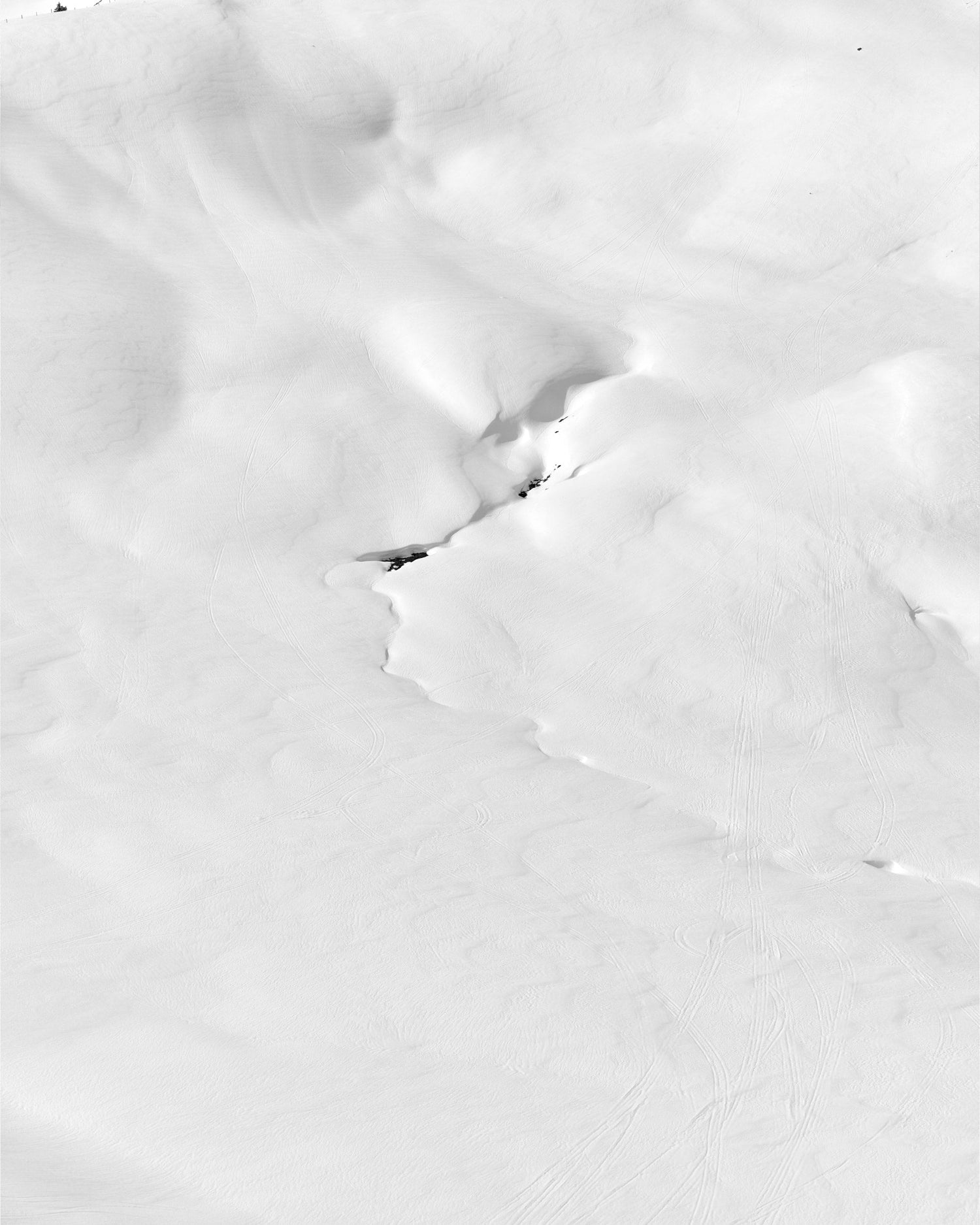 The artpiece 'Riss' by Andreas Ortner shows part of a mountain covered in snow, with a few cracks in the middle of the snow.