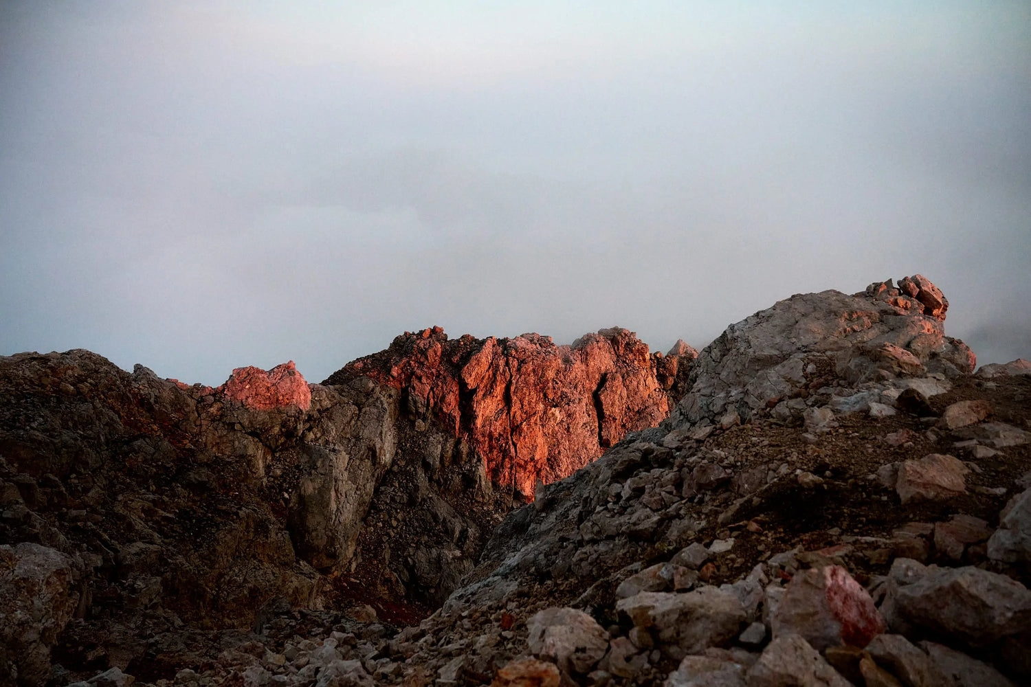 The artpiece 'At World's End' by Chris König shows a rocky landscape in the Julian Alps against a cloudy background.