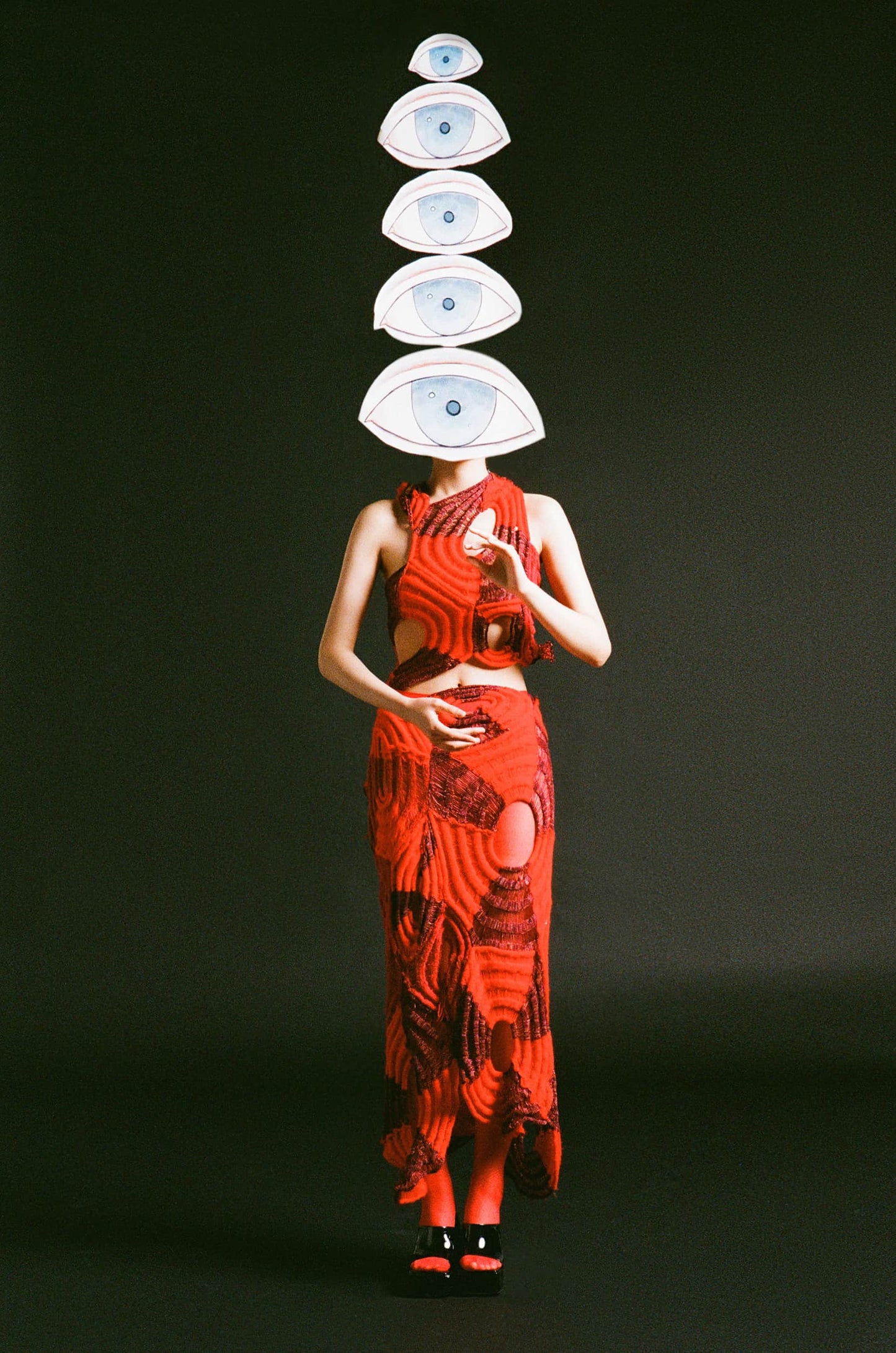 The artpiece 'Hide' by Hui Long shows a woman in a red dress, holding up many all seeing eyes, one of which covered her entire face.