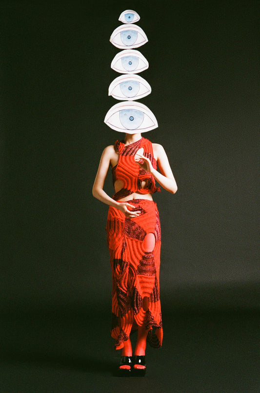 The artpiece 'Hide' by Hui Long shows a woman in a red dress, holding up many all seeing eyes, one of which covered her entire face.