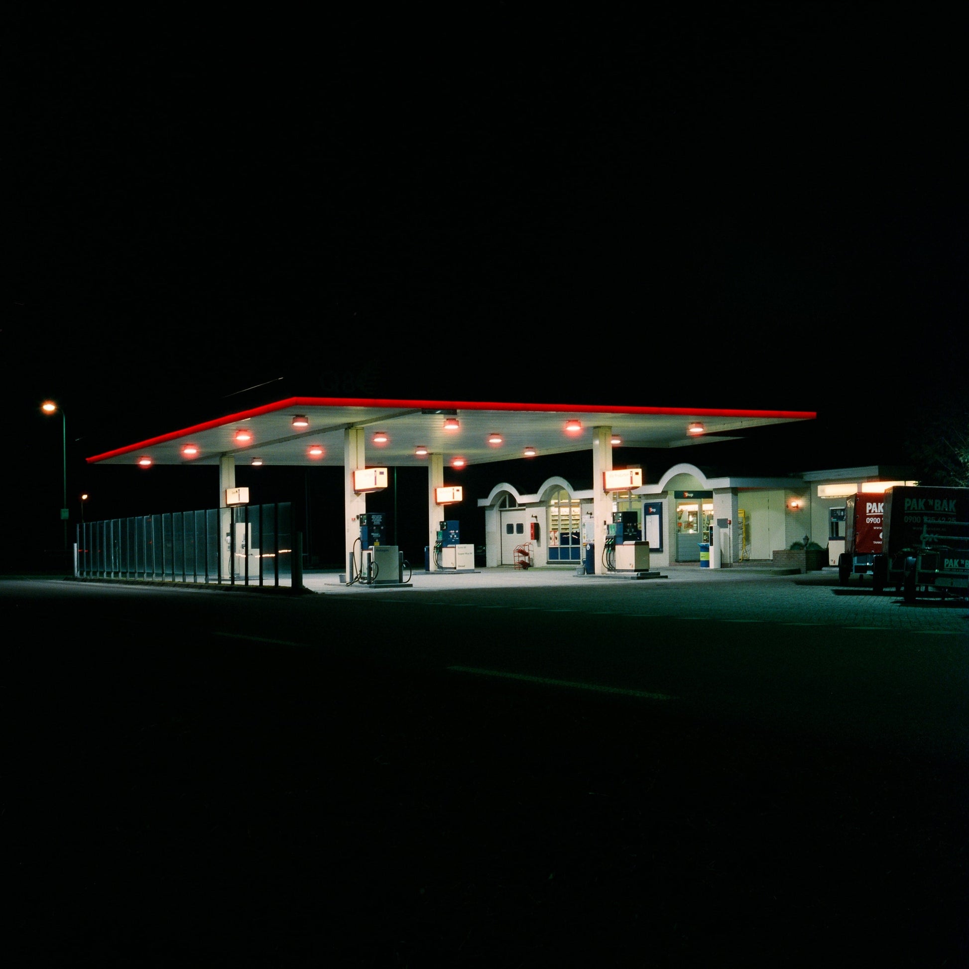 The artwork 'Exterior #1' by Jildo Tim Hof showing a gasstation with bright lights at night surrounded by darkness