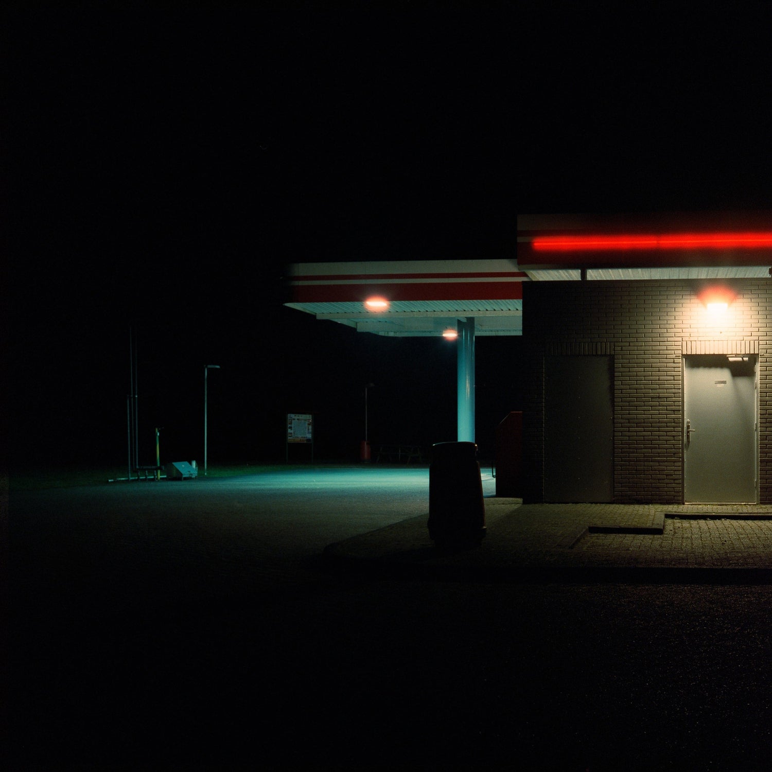 The artwork 'Exterior #2' by Jildo Tim Hof showcasing a deserted parking lot behind a gas station with high contrast lights