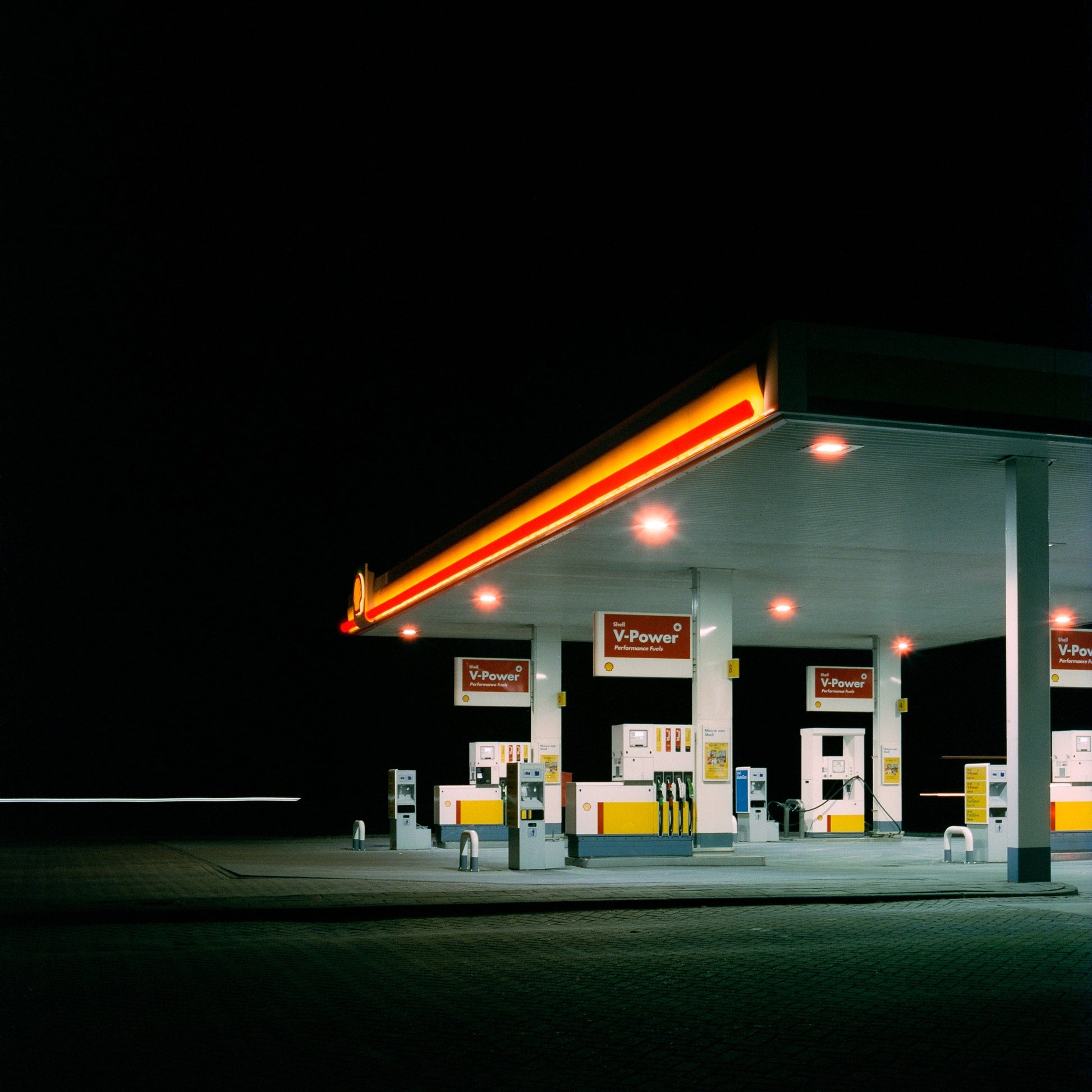 The artwork 'Exterior #7' by Jildo Tim Hof showing a brightly lit deserted Shell gas station surrounded by darkness