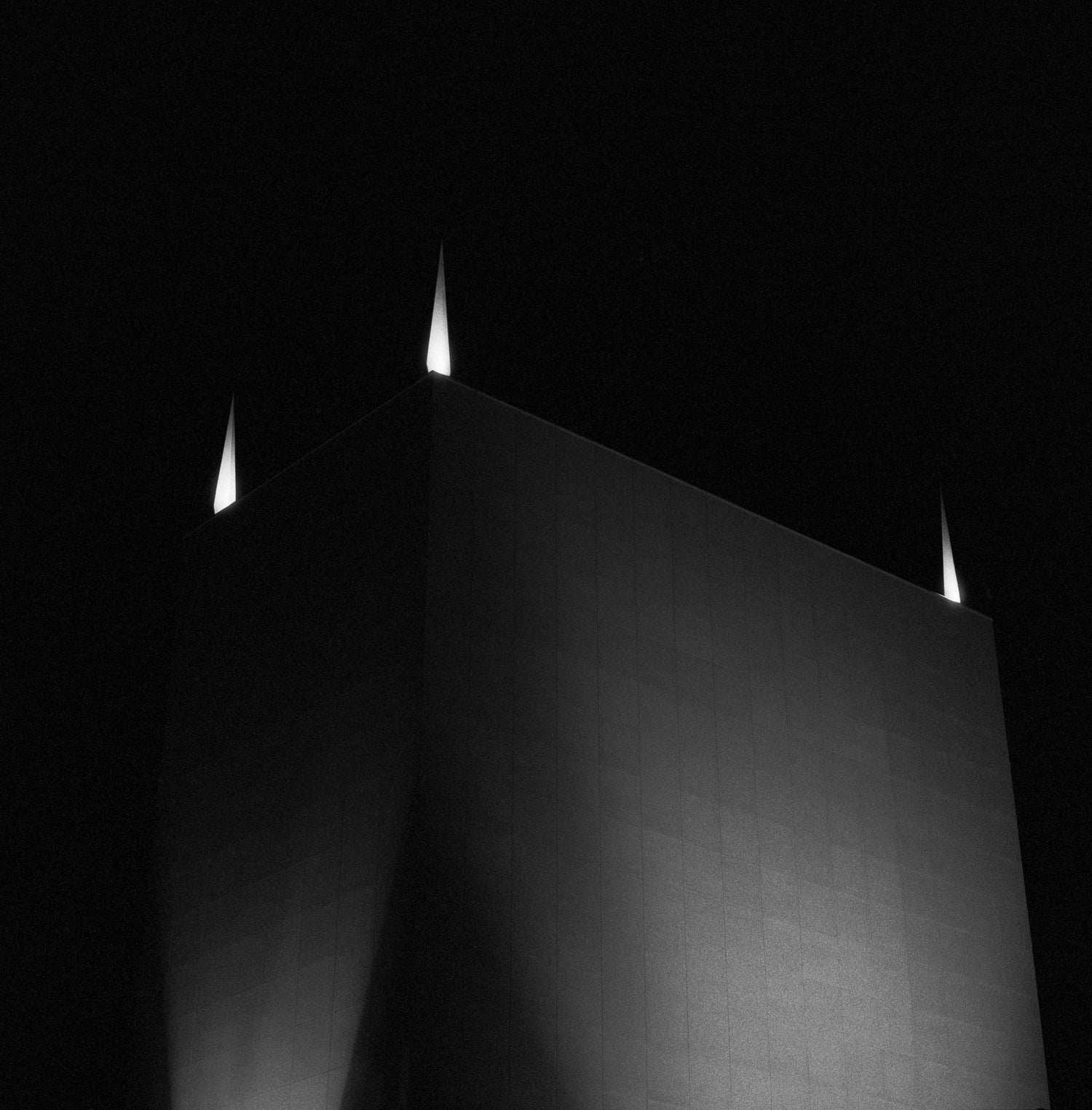 The artwork 'Concrete #1' by Jildo Tim Hof showing a dimly lit concrete building with beams of light going up from the roof