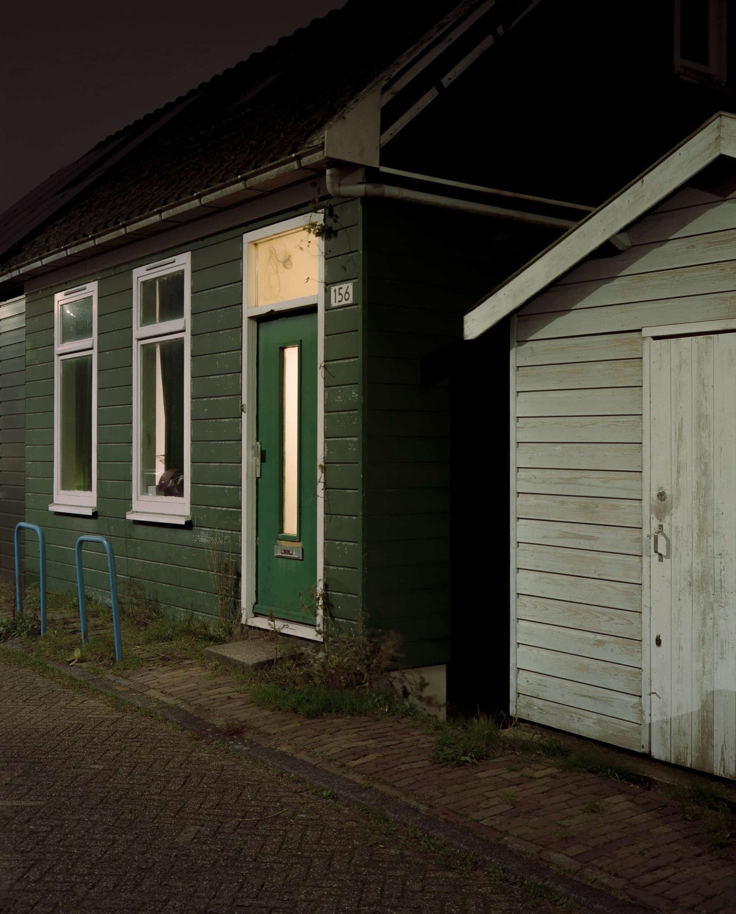 The artpiece 'Amsterdam Noord #4' by Jildo Tim Hof showing an older, green, wooden building in Amsterdam-Noord