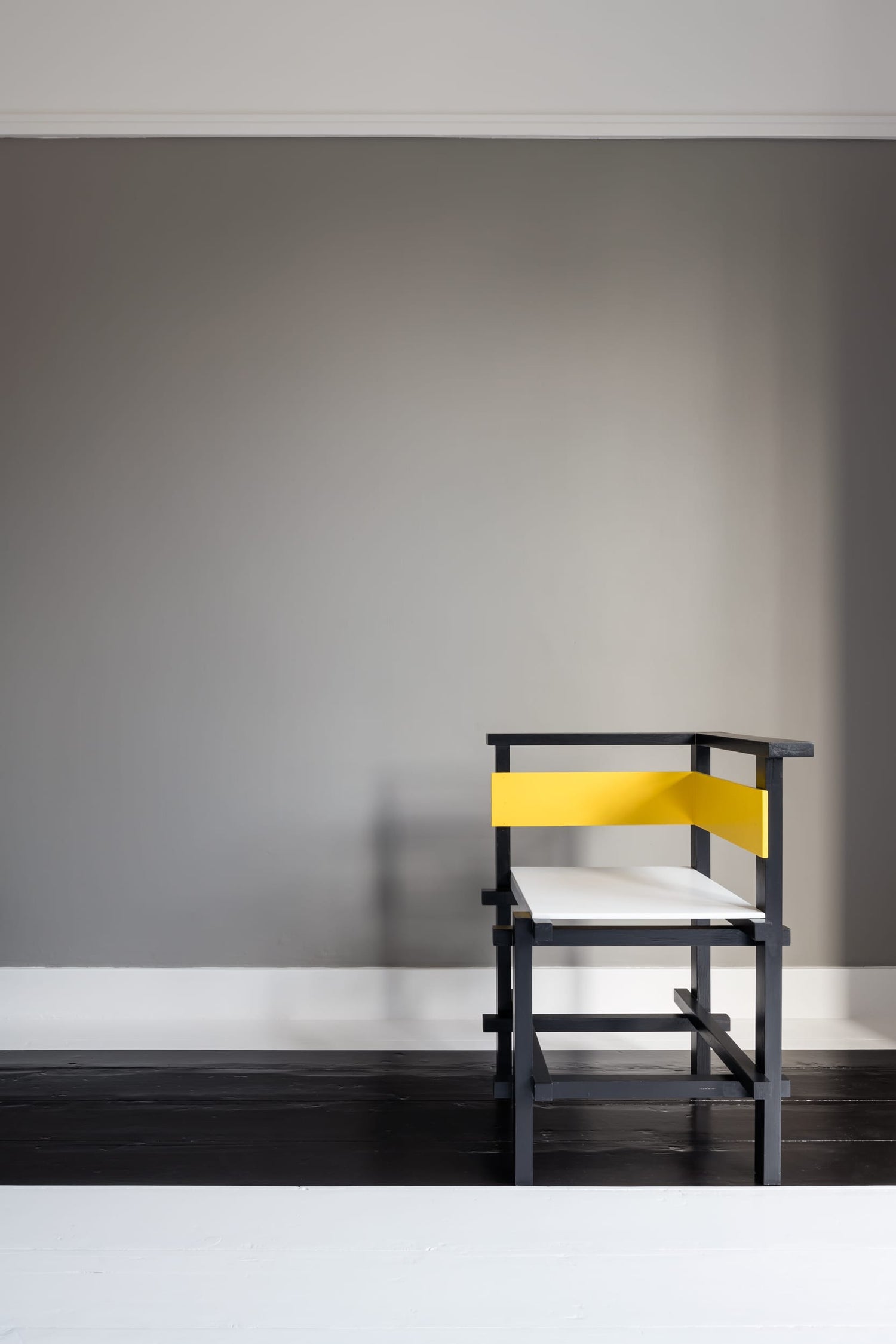 The artwork 'Van Doesburg-Rinsemahuis #4' by J.T. Hof displaying a lonely black and yellow chair deliberately placed in front of a grey wall