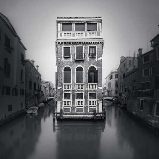 The artpiece 'Palazzo Tetta' by Marco Maljaars shows the famous Palazzo Tetta in Venice in black and white, surround by tranquil waters.