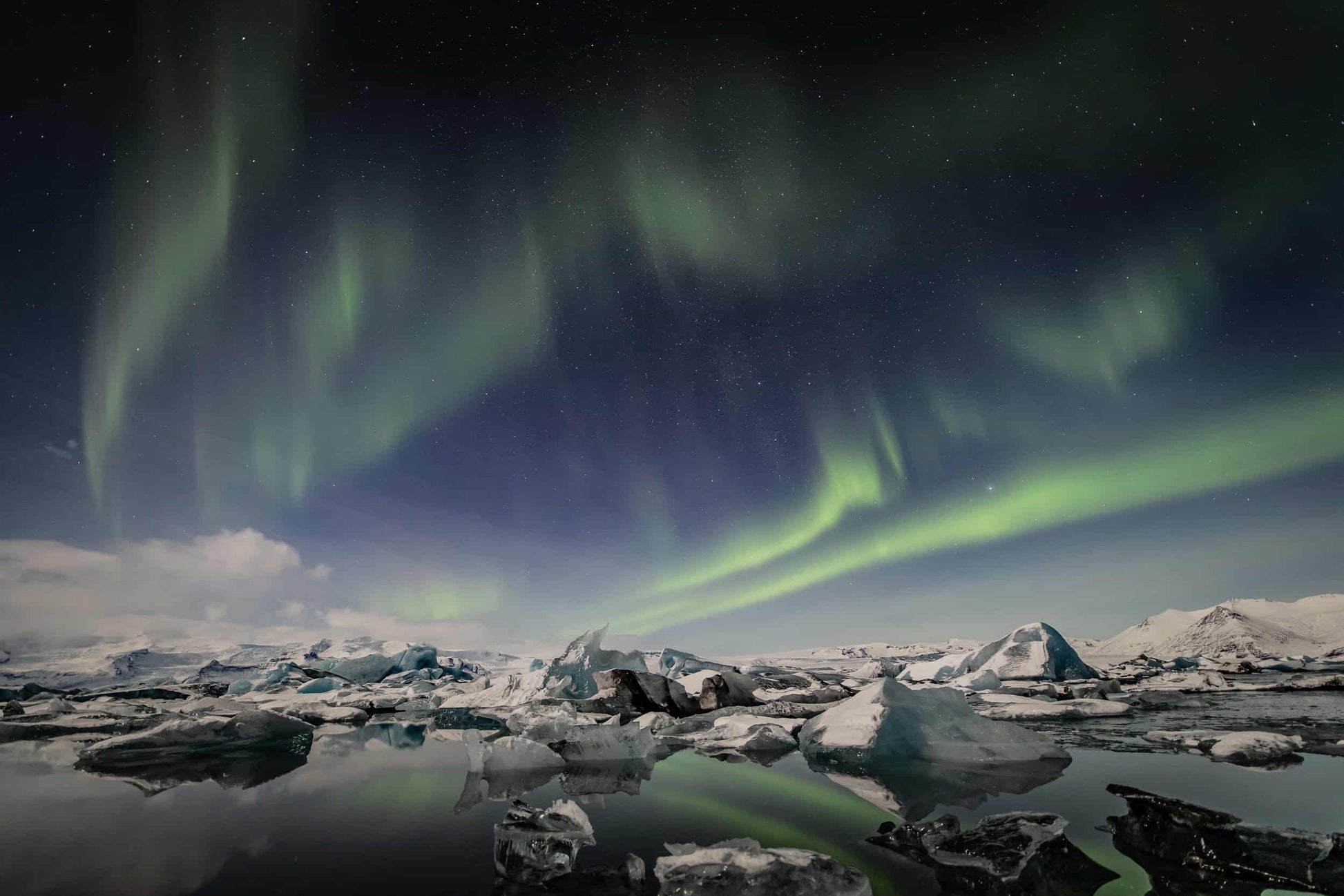 The artpiece 'Jokulvatn' by Markus van Hauten shows a lake at night, with green streaks of the northern lights in the sky.