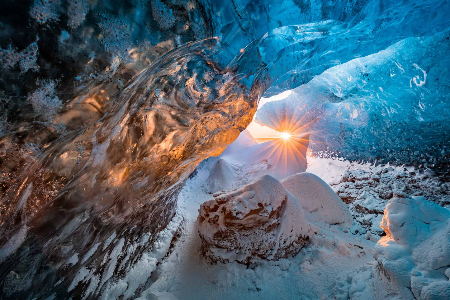 The artpiece 'Dawn of the Cavern' by Markus van Hauten showing a black and bright blue ice cave, with only one light of in the distance.