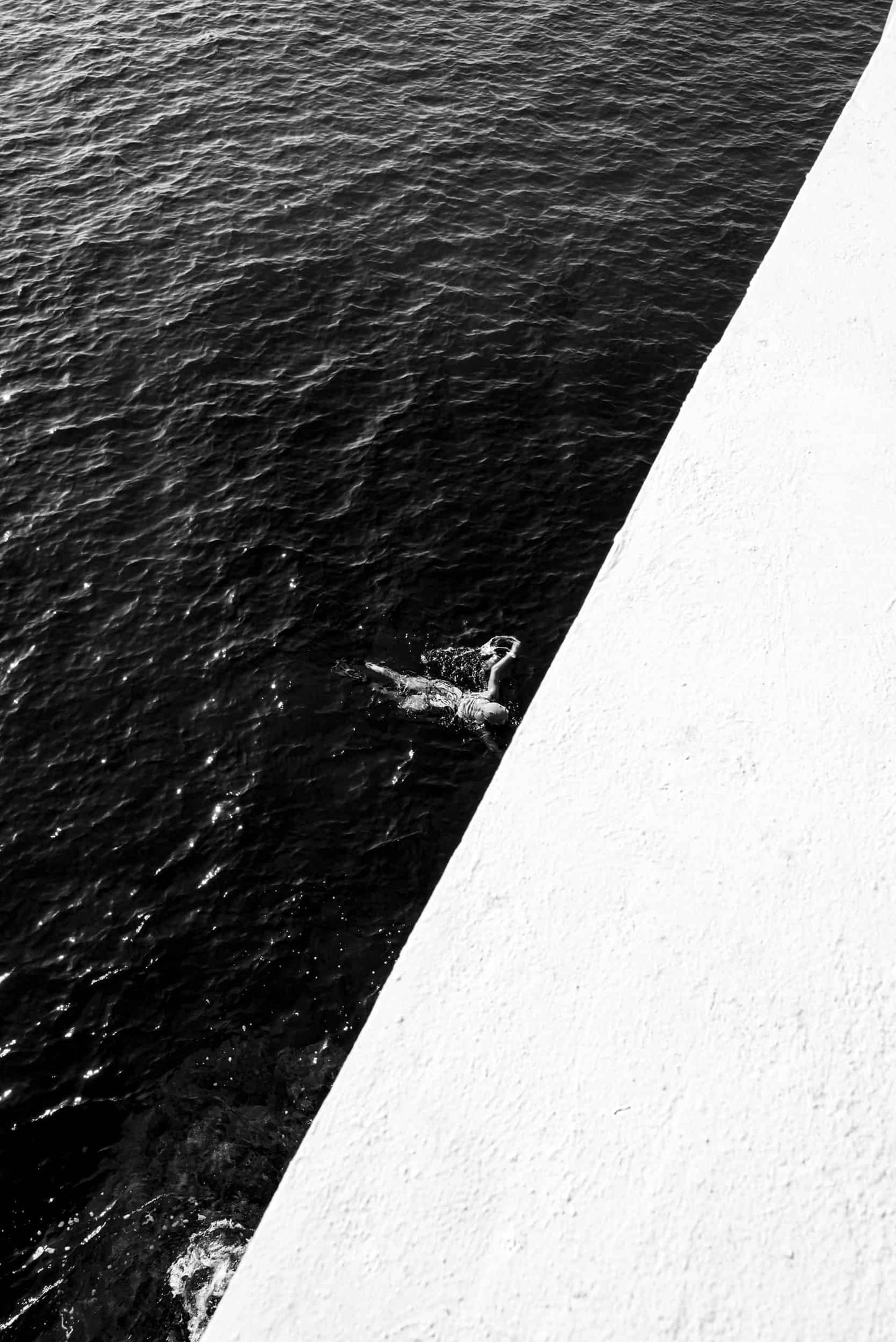 The artpiece 'La Nageuse' by Mathieu Puga is a black and white photograph showing a swimmer in the ocean.