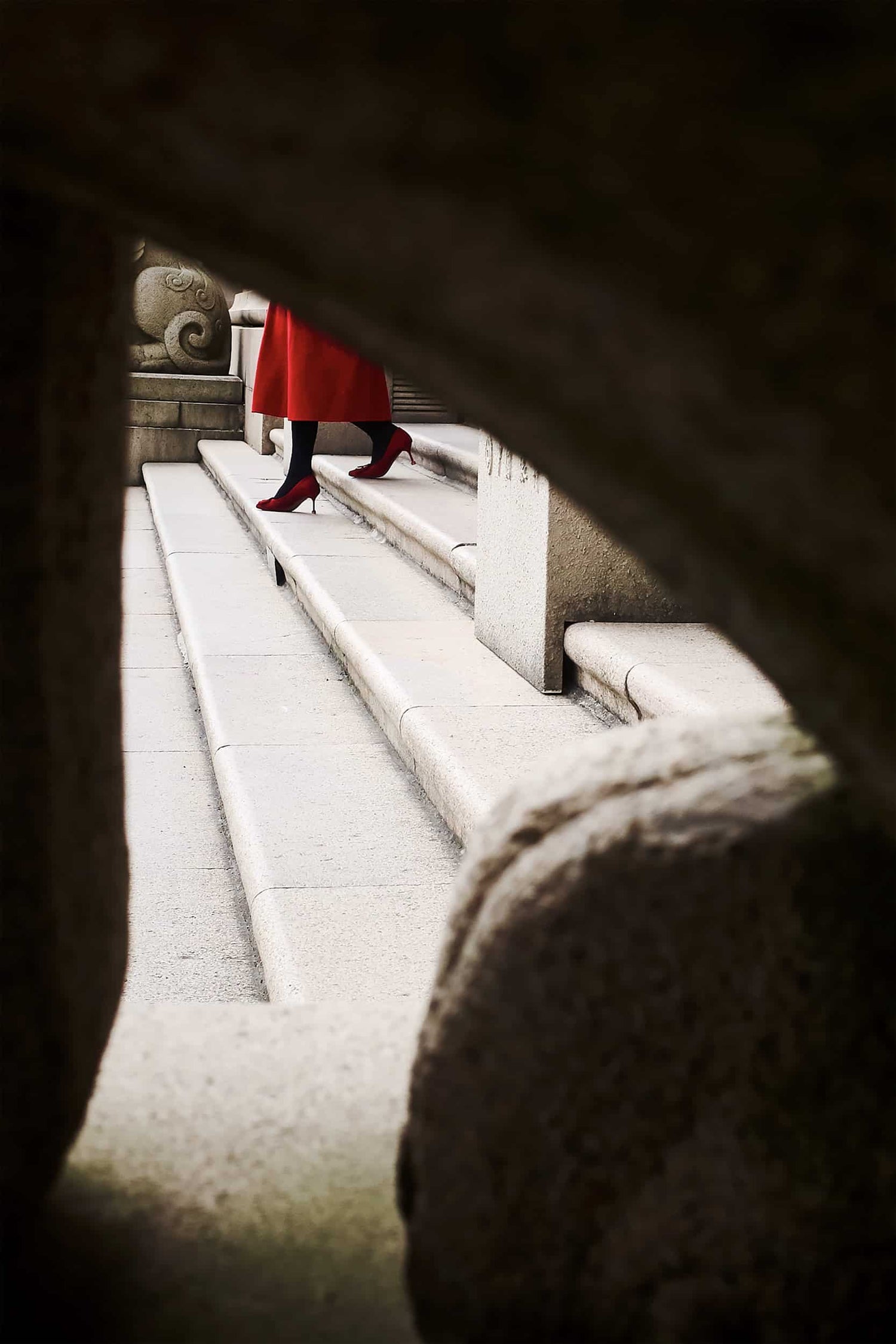 The artpiece 'Dream Girl' by Michael Cai showing a woman in red heels and dress walking down a stone flight of stairs.