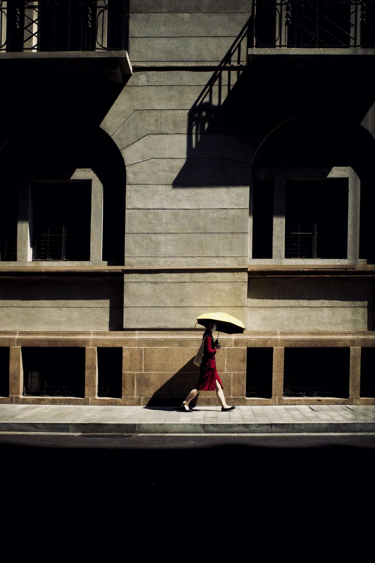 The artpiece 'Imagine' by Michael Cai which shows a woman in a red dress holding an umbrella while walking on the sidewalk.