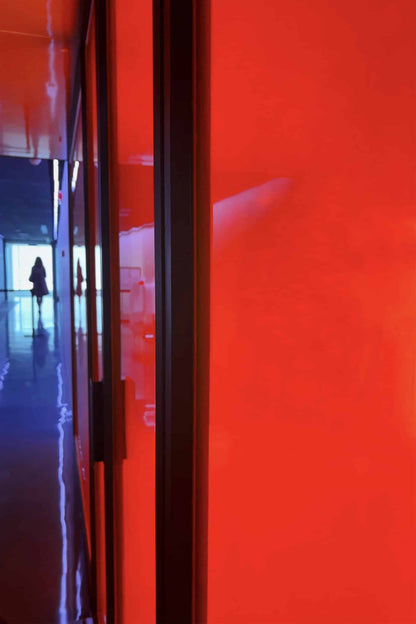 The artpiece 'Limitation' by Michael Cai shows a long bright red wall and someone walking by the wall in the background.
