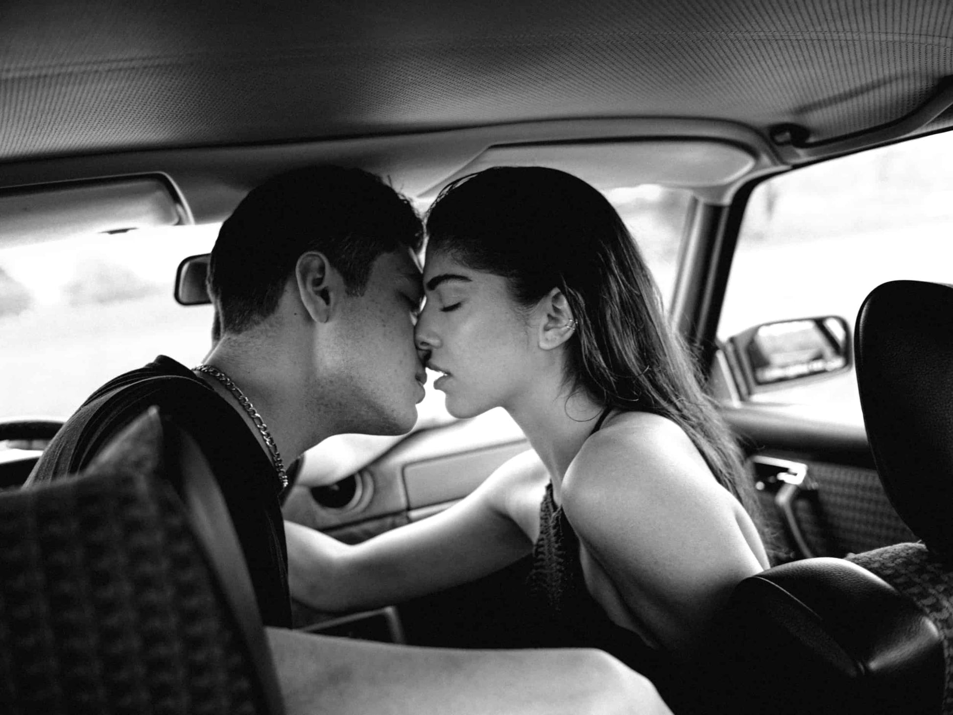 The fine-art piece 'Kiss Me' by Mikail Sahin shows two lovers, giving each other a passionate kiss on the backseat of a classic car.