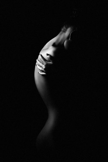 Silhouette of a woman standing, hands wrapped around her body, with a pronounced S-shaped curve, captured in black and white by Ruslan Bolgov