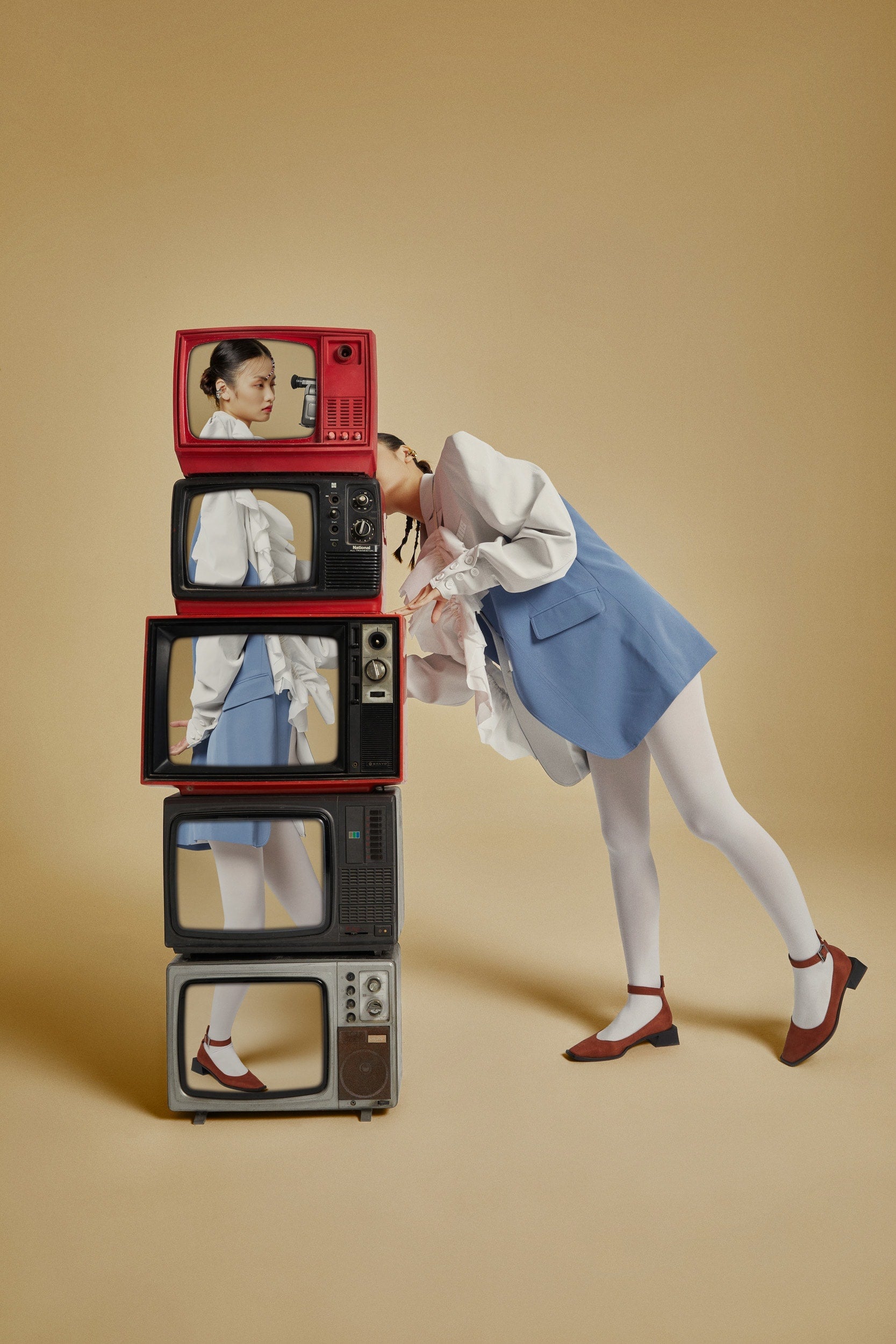 The artpiece 'Snoopy' by Hui Long shows a stack of TV's. Each one showing part of an image of a woman, together they create the entire image. While at the same time the woman is standing next to the TVs and looking at it.