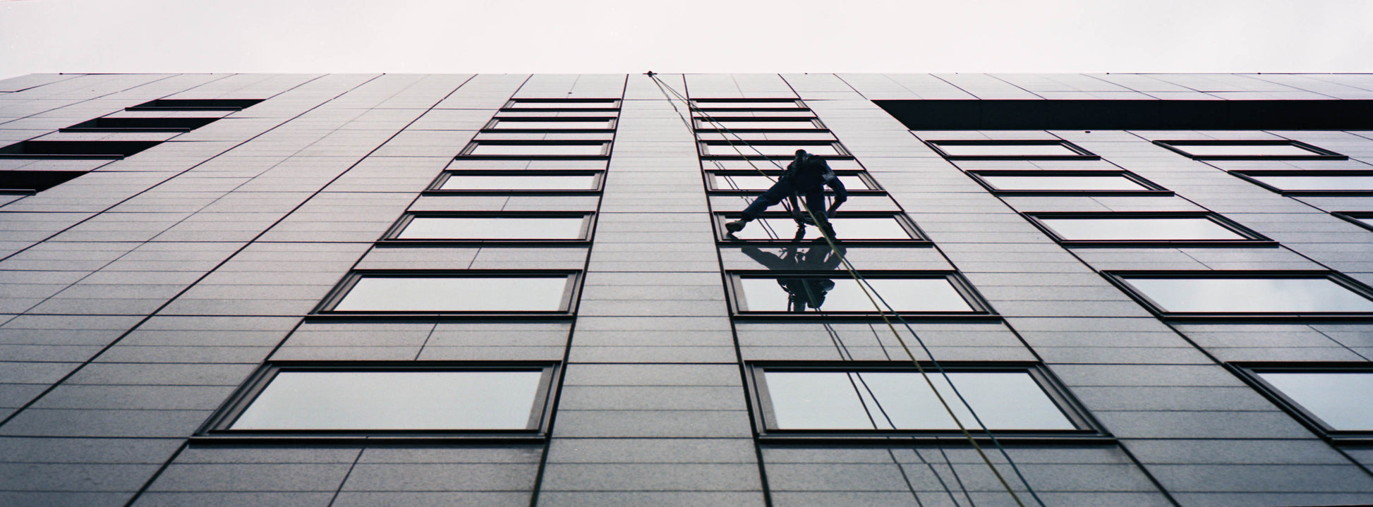 A window cleaner hanging in front of the windows