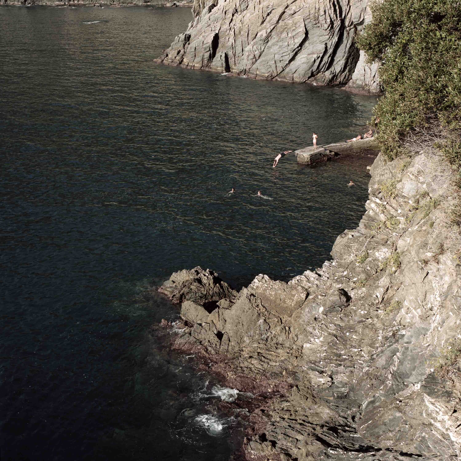 Cliffs in Italy with a man diving in the ocean