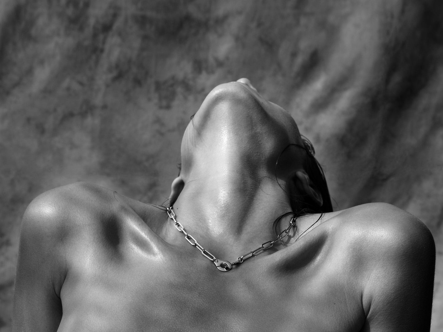 Gianluca Fontana's 'Waves' - Close-up portrait of a woman's upper chest and neck adorned with a delicate necklace, dark grey background, part of the Krops collection, created in Paris, 2018