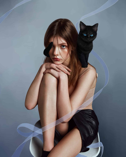 The artpiece 'Cat' by Yang Han shows a woman sitting on a chair with a black cat with blue eyes on her shoulder.
